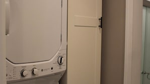 Un espace buanderie équipé d’un lave-linge et d’une armoire haute.