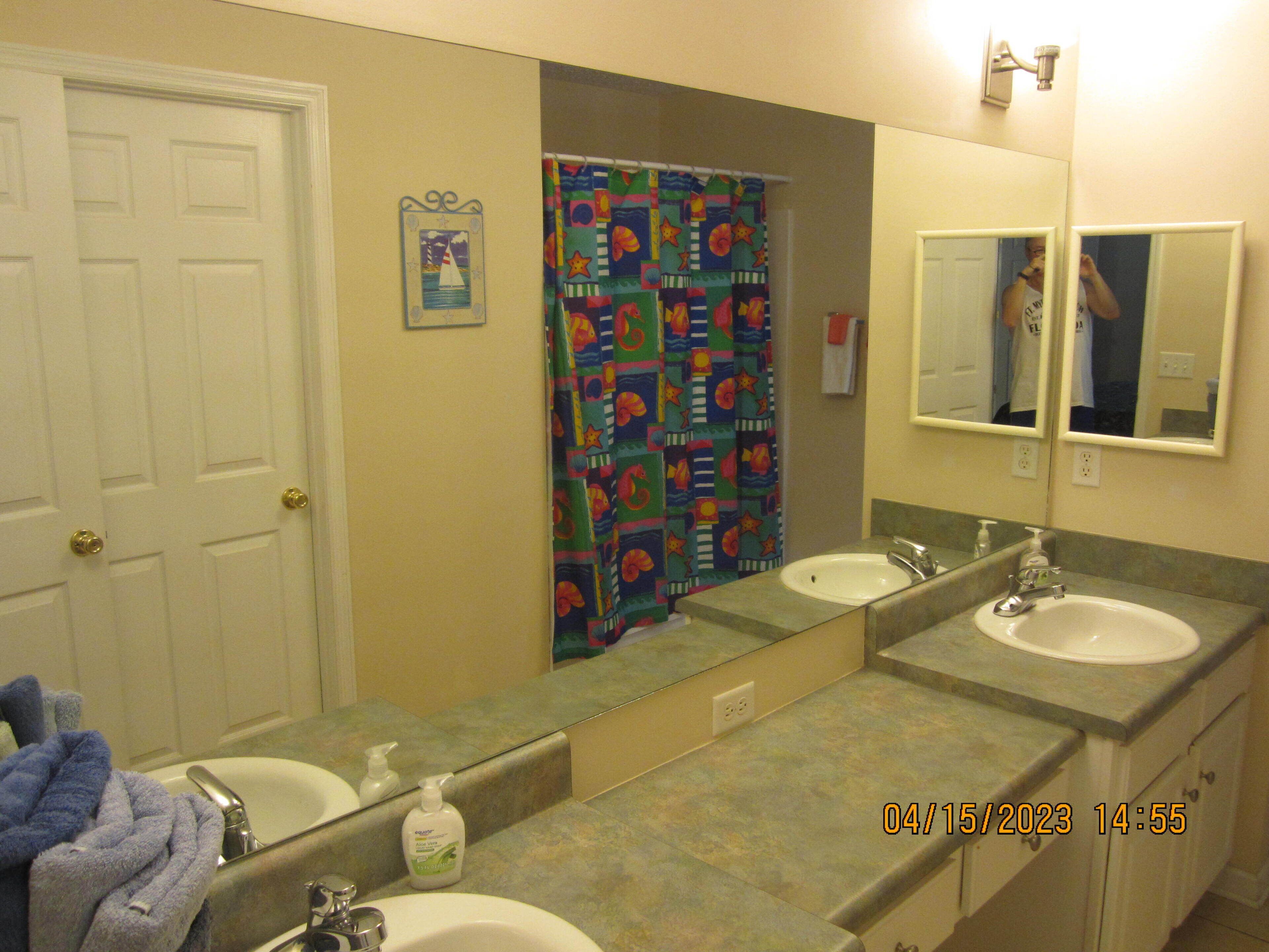A bathroom with two sinks, a mirror, and a shower curtain.