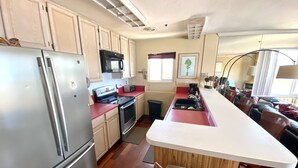 A modern kitchen with stainless steel appliances, a red countertop, and wooden cabinets. - Rarely Available Oceanfront Penthouse (San Diego)
