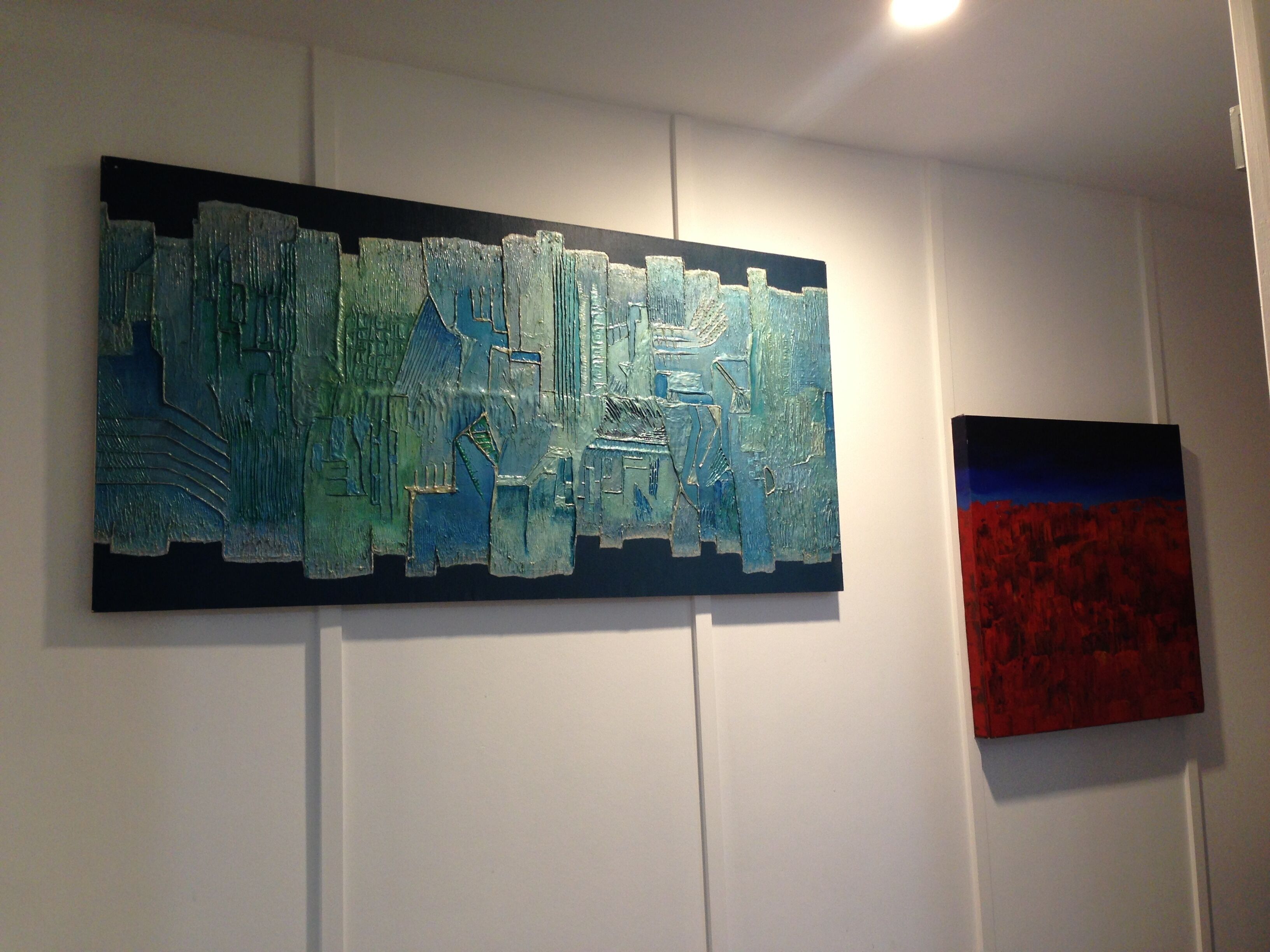 Une pièce dans laquelle on trouve un grand tableau abstrait au mur et un tableau plus petit en dessous.