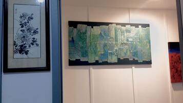A wall with two artworks: a framed black and white floral print and a textured abstract painting.
