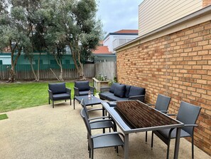 A patio with outdoor furniture, a table, and a brick wall. - Whites Retreat (The Esplanade) (Torquay)