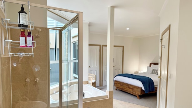 A modern bedroom with a large bed, a glass-enclosed shower, and a view of the outside. - Whites Retreat (The Esplanade) (Torquay)
