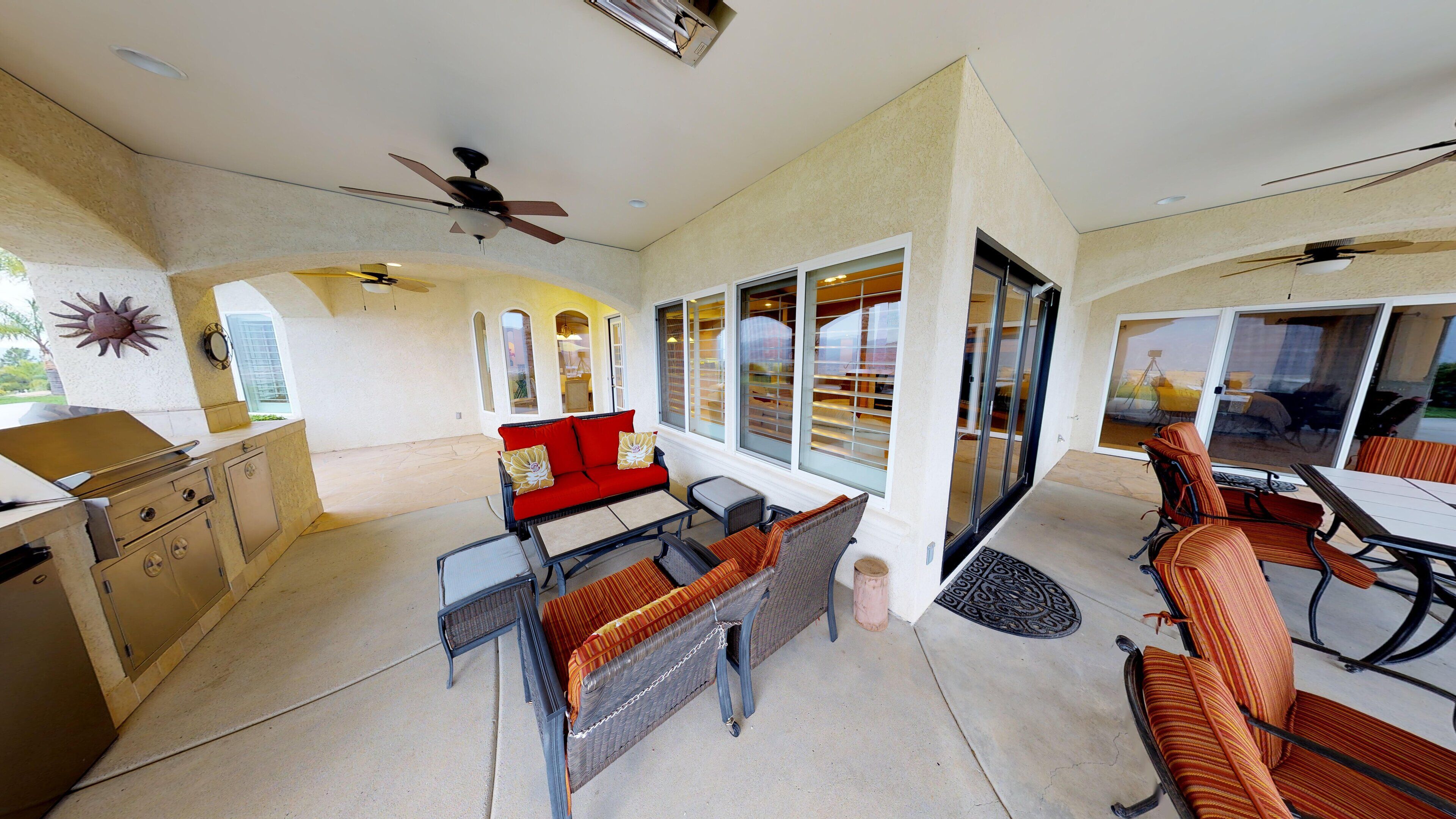 A spacious patio area with a dining table, chairs, a sofa, and a grill.