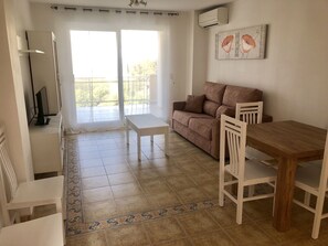 Ein Wohnzimmer mit einer Couch, einem Holzesstisch und einem Fernseher.