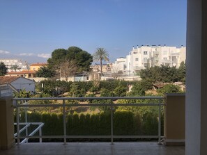A balcony with a view of residential buildings, trees, and a clear sky. - Ideal apartment for families with playground, pool and garden (Denia)