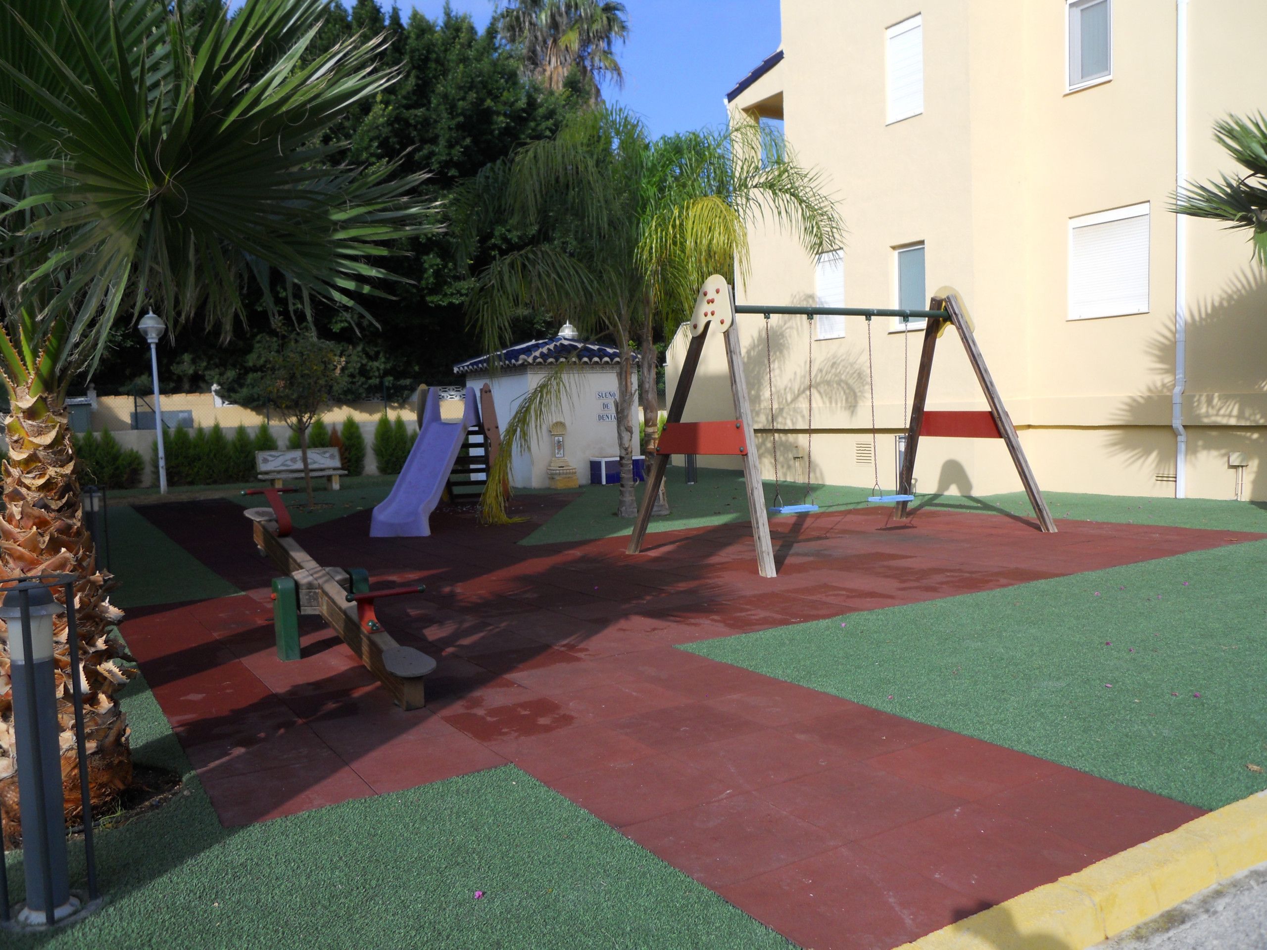 Ein Spielplatz mit Rutsche, Schaukeln und einer kleinen Schutzhütte.