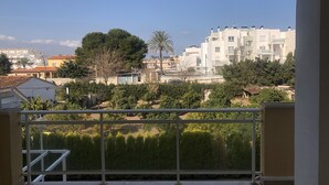 A balcony with a view of residential buildings, trees, and a clear sky.
