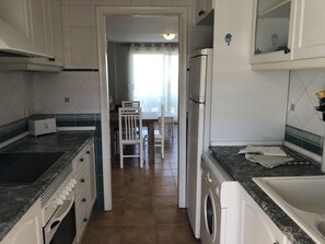 Une cuisine équipée d’un lave-linge, d’un réfrigérateur et d’un coin repas avec des chaises et une table.