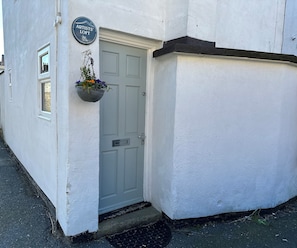 Un edificio blanco con una puerta, una cesta de flores colgante y un letrero que dice 'Artists' Loft'.