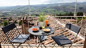 A terrace with a table set for two, overlooking a scenic valley.