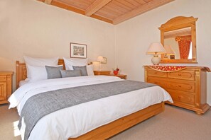 A bedroom with a wooden bed, a dresser with a mirror, and a nightstand with a lamp. - Cozy vacation apartment in Ahlbeck with a small garden - only 400 m to the beach! (Seebad Ahlbeck)