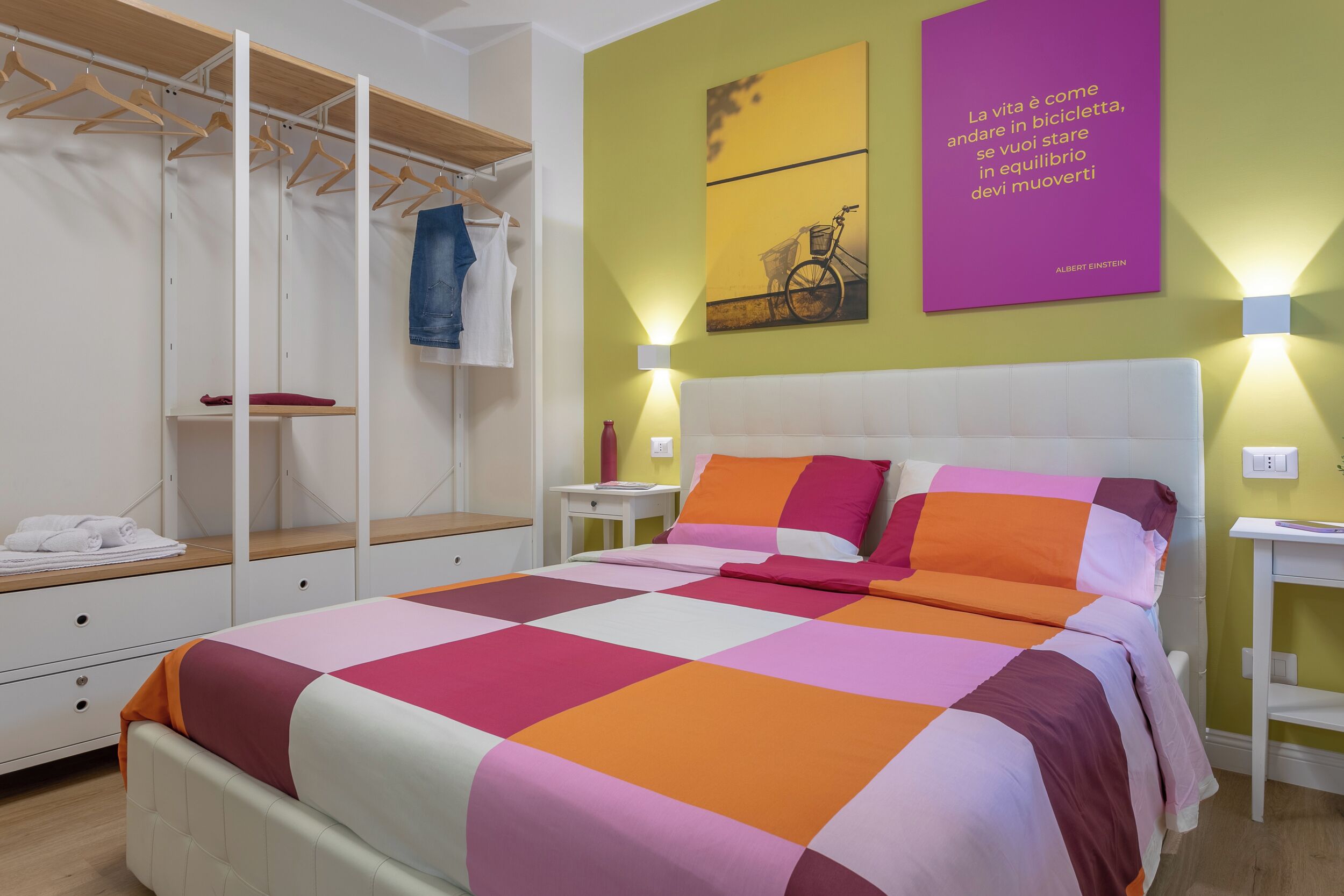 Une chambre avec un lit, une armoire et un mur orné d’une citation.