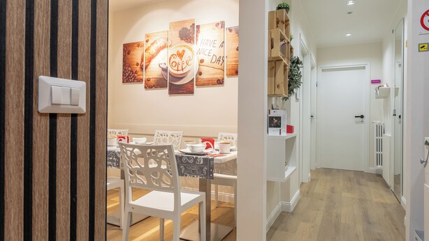 A dining area with a wooden table and chairs, a wall with coffee-themed artwork, and a white door in the background. - B&B Pensieri D'Autore (Campobasso)