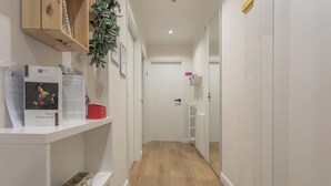 A hallway with white walls, a wooden floor, and a door at the end. Shelves on the left hold papers and a red container. - B&B Pensieri D'Autore (Campobasso)