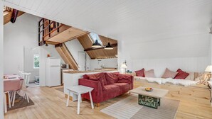 Un loft ampli amb un sostre alt, una zona de cuina, un espai per dinar i una sala d'estar amb un sofà vermell i un canapè blanc.