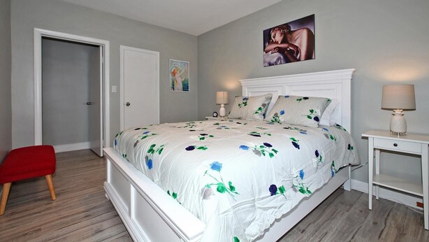 Ein Schlafzimmer mit einem großen Bett, einem Nachttisch, einem roten Sessel und einer Tür.