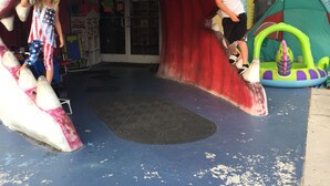 Un área de juegos con una entrada tipo túnel, un tobog án inflable pequeño y una estructura inflable colorida.