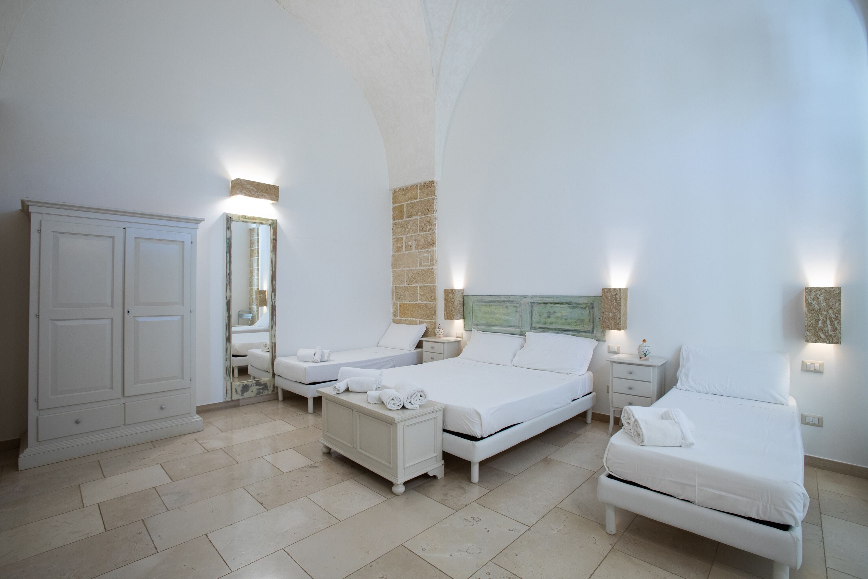 A bedroom with two beds, a wardrobe, and a mirror.