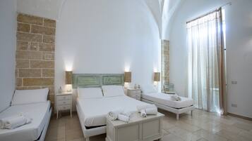 Habitación de hotel con tres camas, un espejo grande y una pared de piedra.