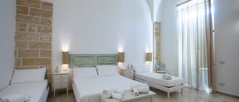 A hotel room with three beds, a large mirror, and a stone wall.