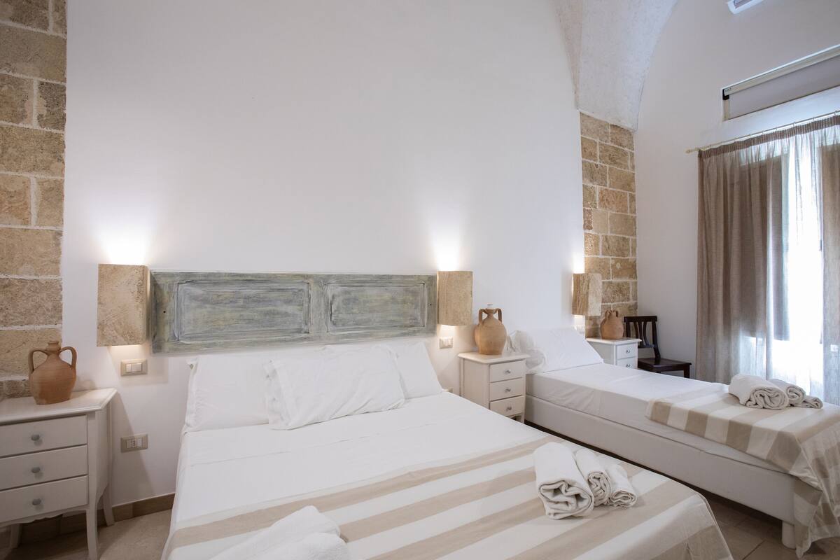 A hotel room with two beds, a stone wall, and a rustic headboard.