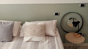 A neatly arranged bedroom with a bed, pillows, a bedside table with a lamp, and framed artwork on the wall. - Imperia, two-bedroom apartment, nature, and reax (Imperia)