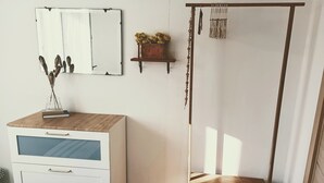 A room with a white dresser with drawers, a small wooden table, a mirror, and a shelf with decorative items. - Imperia, two-bedroom apartment, nature, and reax (Imperia)