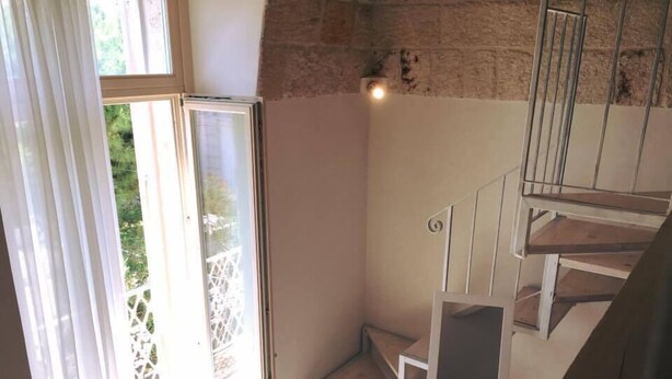 Una escalera con barandilla blanca y vistas al follaje exterior.