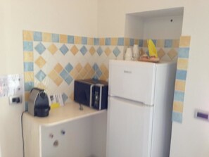 Una cocina compacta con refrigerador, microondas y una pequeña encimera.