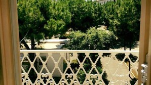 Un balcón con vista a un jardín con diversos árboles y arbustos.