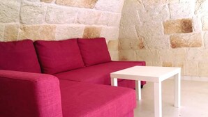 Un sofá rojo y una mesa blanca en una habitación con pared de piedra.