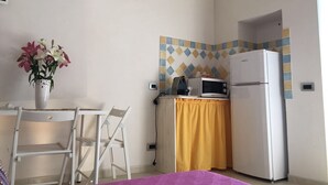 Una cocina compacta equipada con microondas, refrigerador y un pequeño comedor con una silla y una mesa.