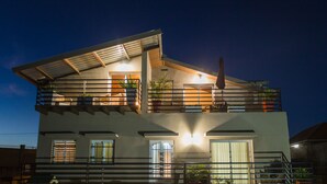 Ein modernes, zweistöckiges Haus mit Balkon, großen Fenstern und einer gut beleuchteten Eingangspartei.