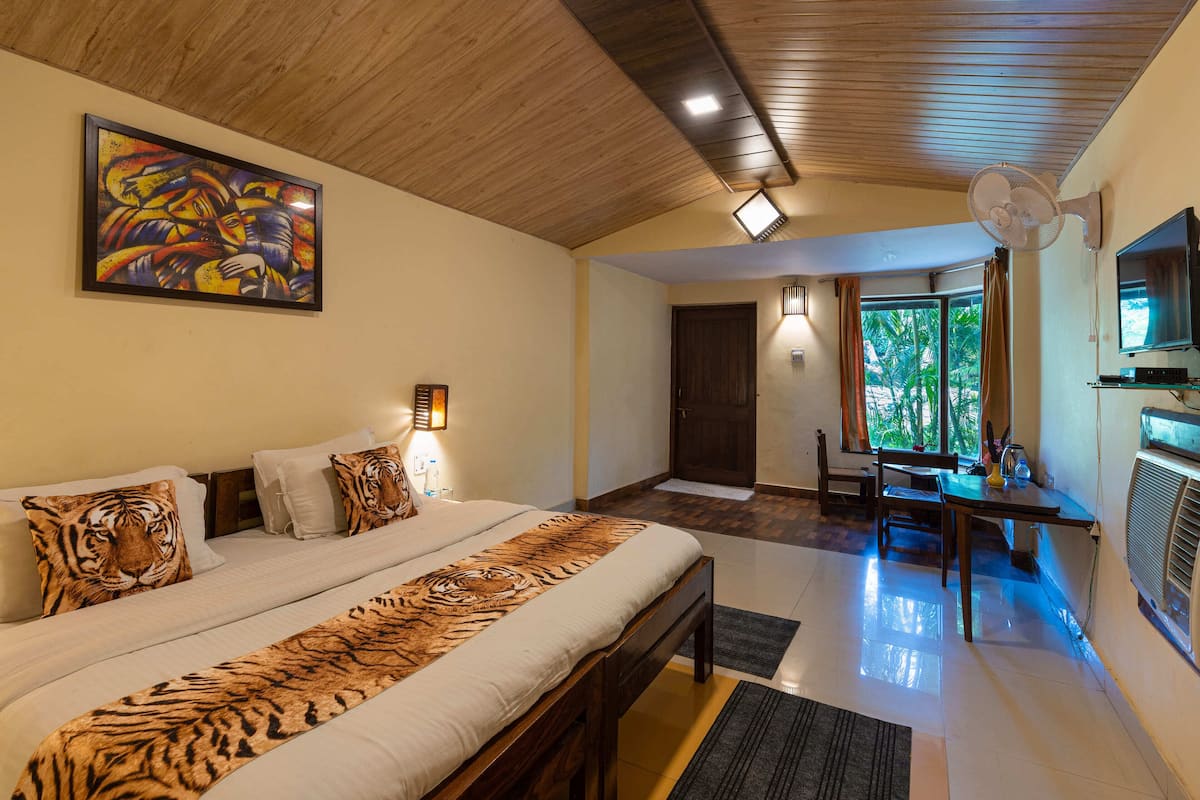 Un dormitorio con una cama grande, un cojín con diseño de tigre, un cuadro y una zona de comedor con mesa y sillas.