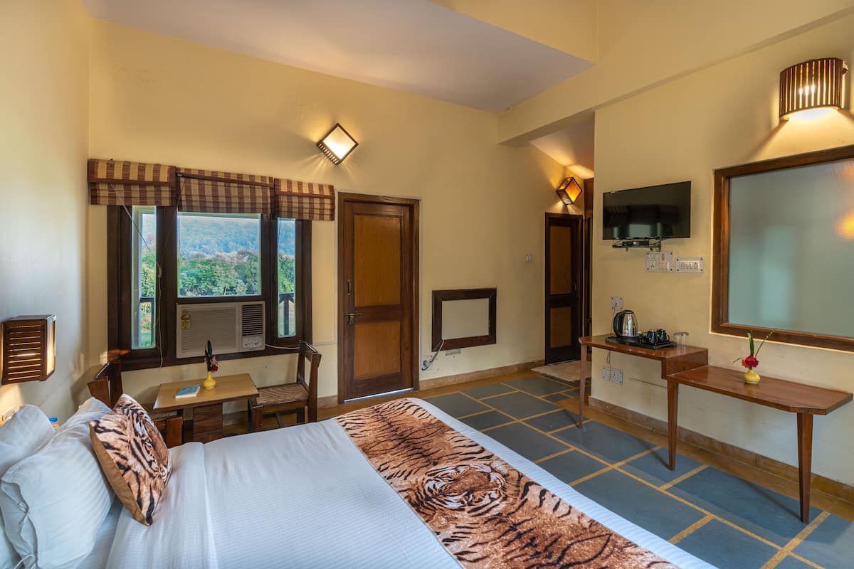 Habitación de hotel con cama, escritorio, silla, televisor y ventana con vistas.