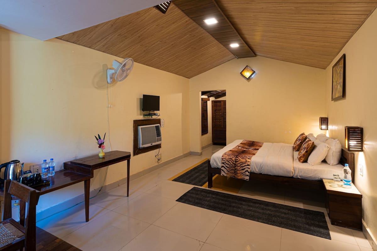 Una habitación de hotel con cama, mesita de noche, silla, escritorio y televisor.