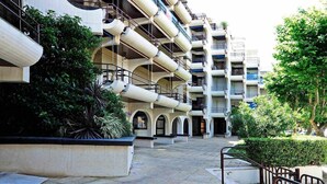 A multi-story hotel with balconies, outdoor seating, and greenery. - Ocean View-São Pedro Estoril - Checkinhome (São Pedro do Estoril)