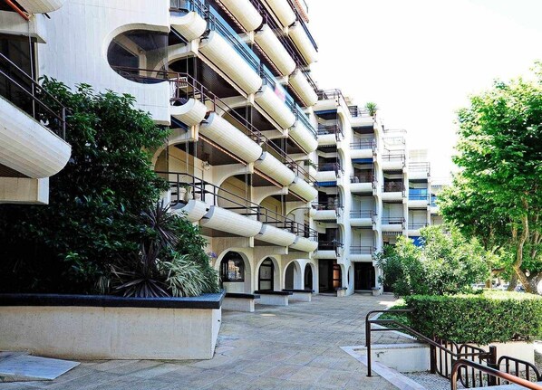 A multi-story hotel with balconies, outdoor seating, and greenery.