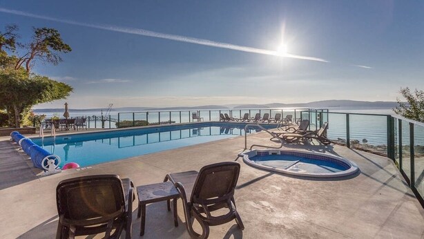 Ein Poolbereich mit Liegestühlen und Meerblick.