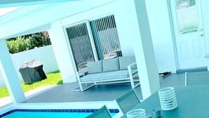 A poolside area with a pool, a covered seating area, and a table with chairs. - SHORT WALK TO BEACH AND RESTAURANTS HEATED POOL (Lauderdale-By-The-Sea)
