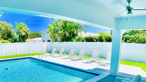 A pool area with a seating area, including a sofa and a table, and a ceiling fan. - SHORT WALK TO BEACH AND RESTAURANTS HEATED POOL (Lauderdale-By-The-Sea)