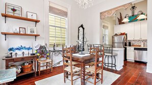 A dining area with a wooden table and chairs, a chandelier, and a view of the kitchen. - New Orleans charm with Gated Parking! (New Orleans)