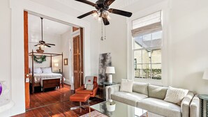 A spacious living room with a glass coffee table, a sofa, a chair, and a ceiling fan. - New Orleans charm with Gated Parking! (New Orleans)