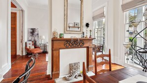 A spacious room with a wooden floor, a large mirror, a fireplace, and a view of the outside through large windows. - New Orleans charm with Gated Parking! (New Orleans)