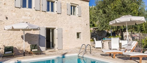 Relax by the serene pool surrounded by lounge chairs and umbrellas.