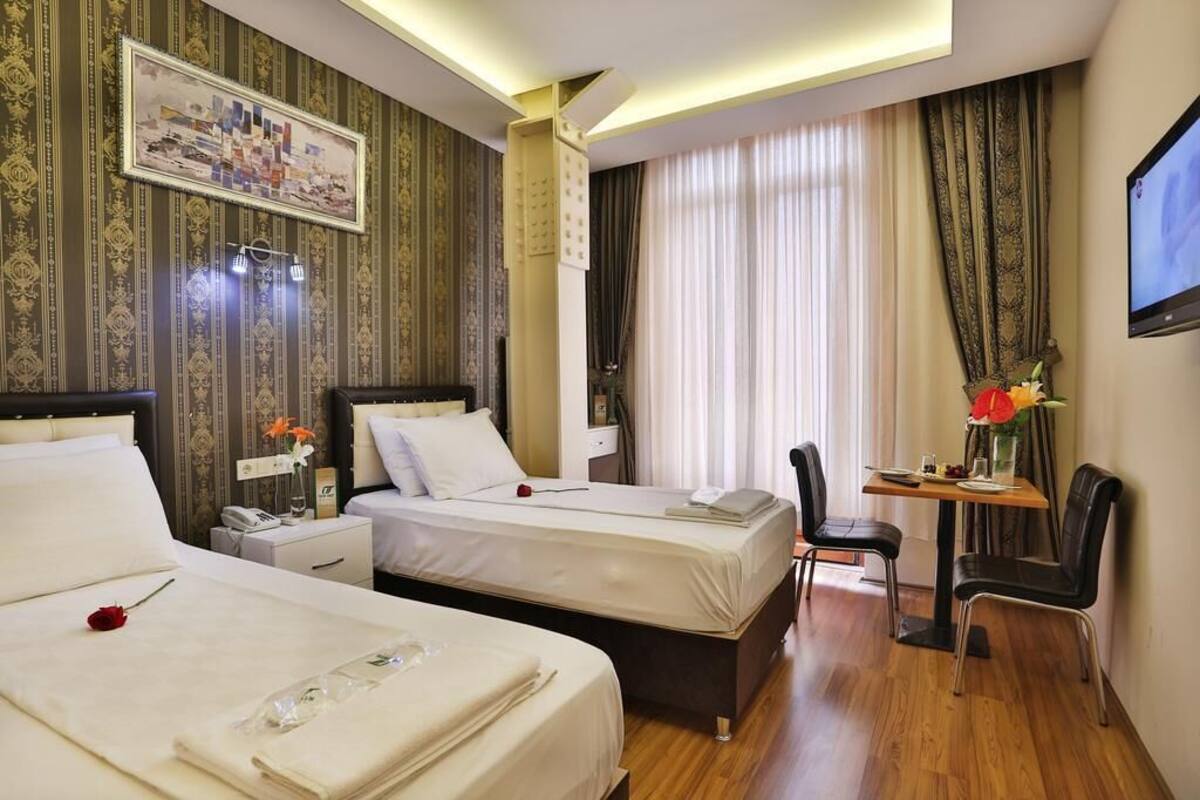 A hotel room with two beds, a desk, and a chair.