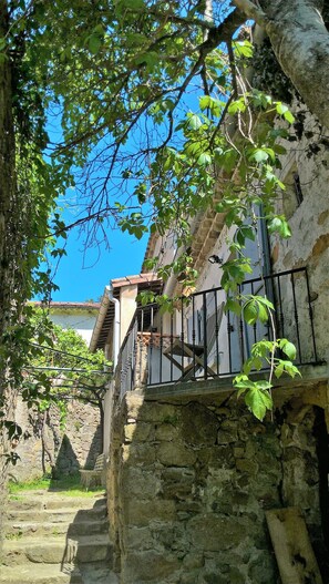 A stone staircase leading to a building with a balcony, surrounded by greenery and a clear blue sky. - Iris On a hillside gite sleeps 4 Mas EDEN Unobstructed view (Thoiras)