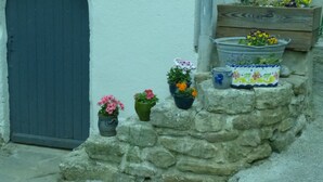 Un muro de piedra con plantas en macetas y un banco de madera.