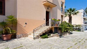 A building with a stone staircase leading to a balcony with potted plants.